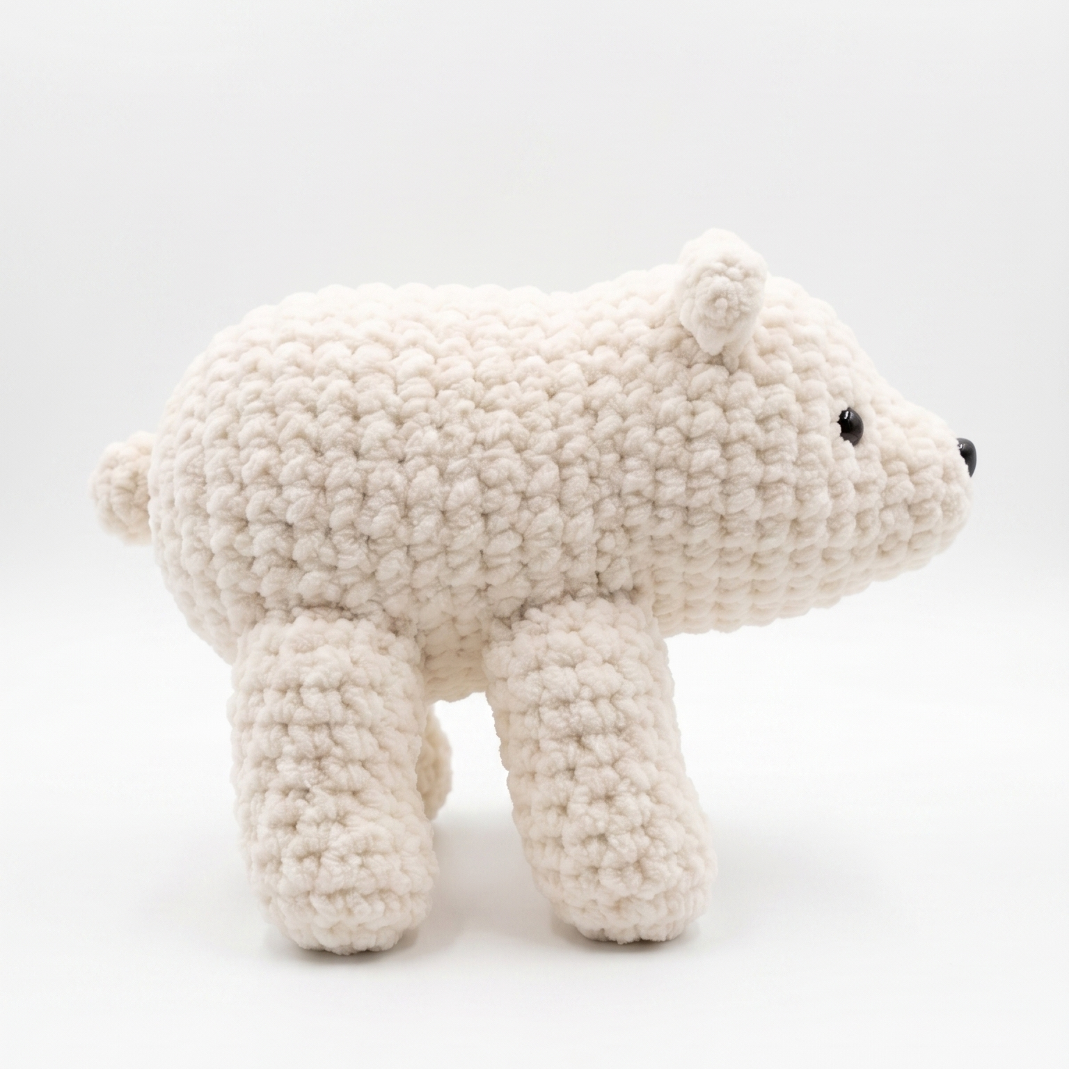A handmade crocheted polar bear toy in off-white, shown from the side against a clean white background.