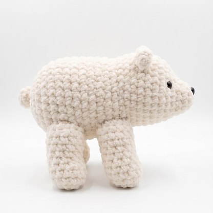 A handmade crocheted polar bear toy in off-white, shown from the side against a clean white background.